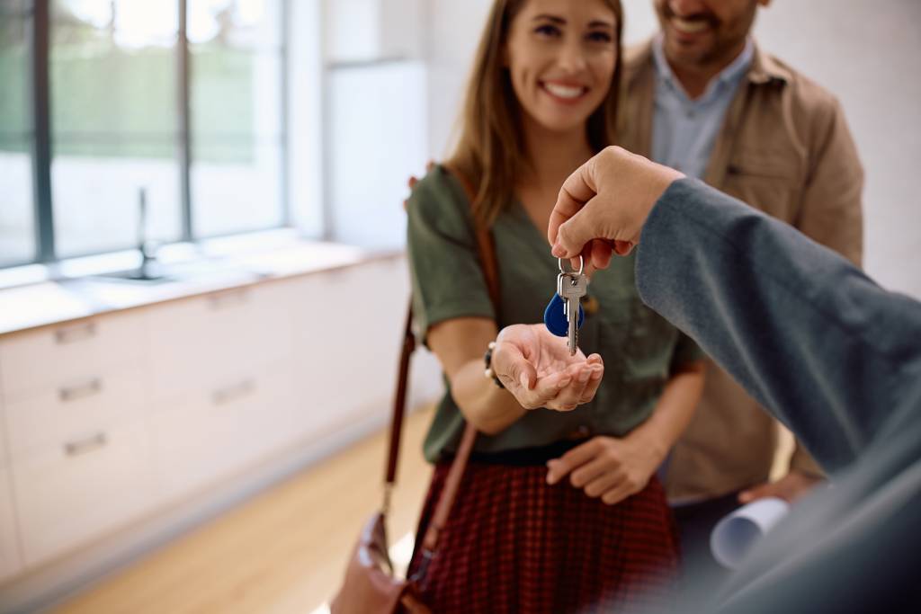 Close up of real estate agent handing over keys to a new home to a couple